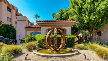 A courtyard with a central fountain, surrounded by gravel and various plants.
