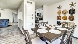 Un comedor con una mesa de madera, individuales blancos y una pared decorada con varios sombreros.