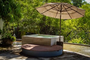A rectangular pool with a wooden deck and a large umbrella.
