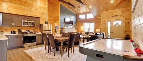 Interior espacioso de una cabaña de madera con cocina, comedor y mesa de billar.