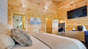 A wooden-paneled room with a bed, a flat-screen TV, and a dining area. - 1 Mi to Douglas Lake: Blissful Escape w/ Hot Tub! (Sevierville)