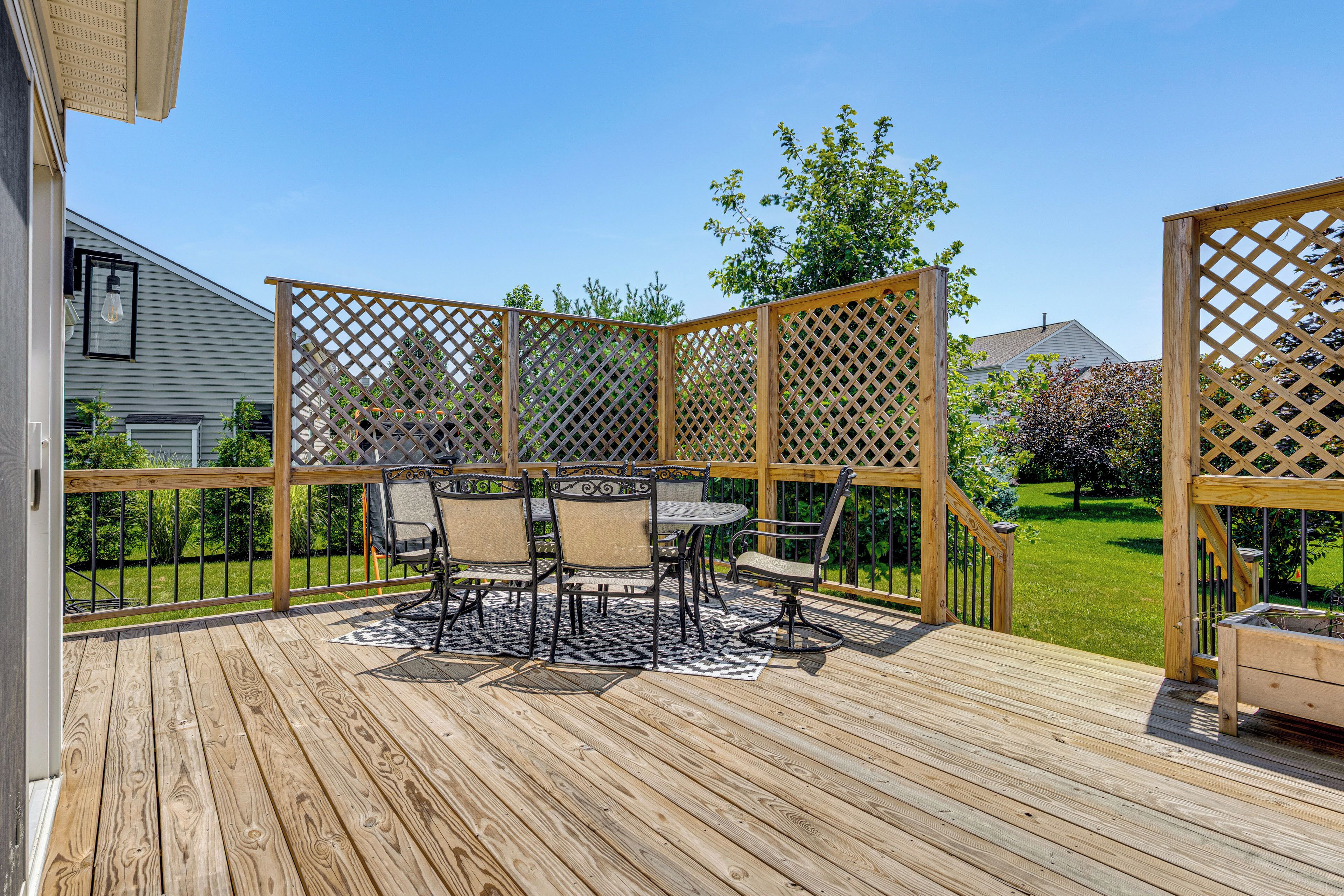 Une terrasse en bois avec une table et des chaises, entourée d’une clôture en treillis de bois.