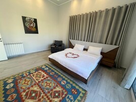 Un moderno cuarto de hotel con una cama grande, un tapete estampado, un cuadro en la pared y vistas de la ciudad a través de la ventana.