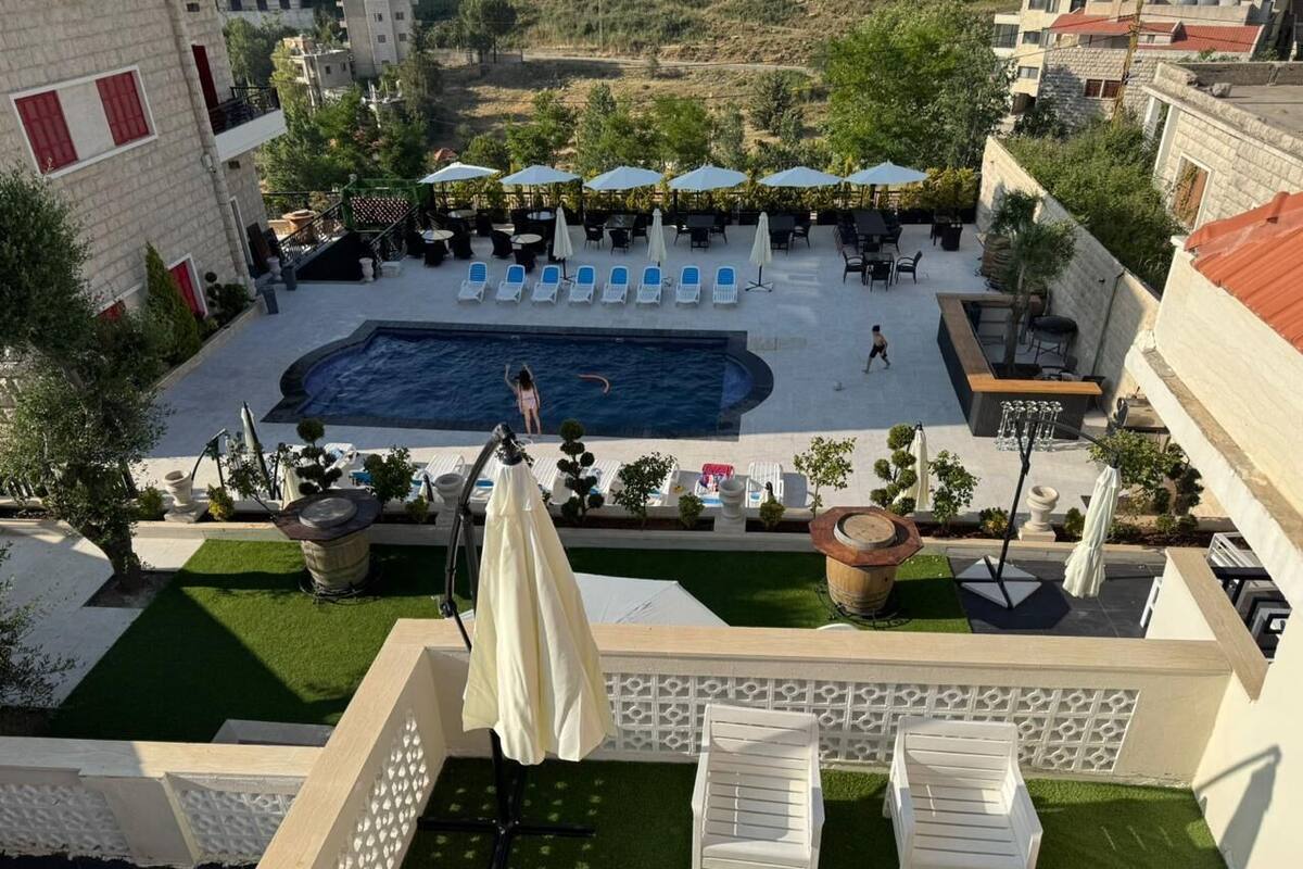 A rooftop pool area with lounge chairs, umbrellas, and a swimming pool.