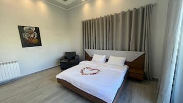 Un dormitorio moderno con una cama grande, cabecera, mesita de noche, radiador y un cuadro en la pared.