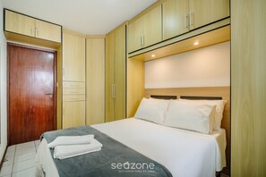 Un dormitorio con cama, armario de madera y una puerta.