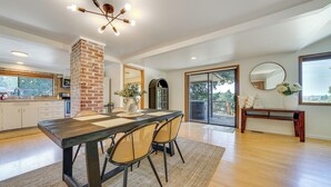 A spacious kitchen with a brick column, a dining area with a wooden table and chairs, and a large window with a view of the outdoors. - 1/2 Mi to Yarrow Bay: Family Home in Kirkland (Kirkland)