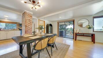 A spacious kitchen with a brick column, a dining area with a wooden table and chairs, and a large window with a view of the outdoors.