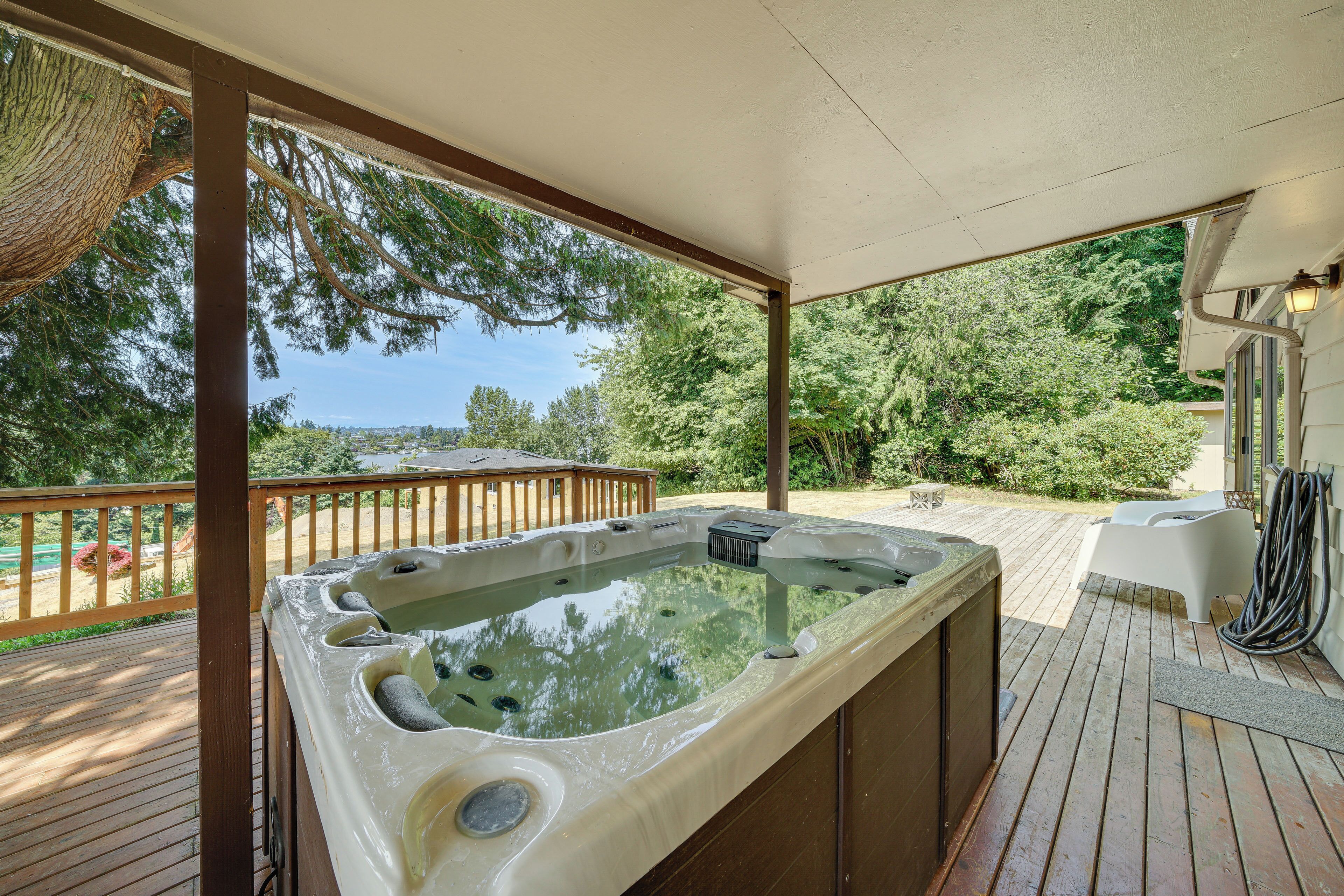 Jacuzzi en una terraza de madera con vistas a árboles y un paisaje lejano.