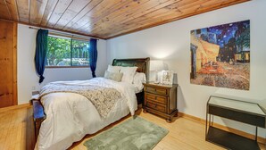 A bedroom with a wooden ceiling, a bed with white linens, a nightstand with a lamp, and a painting on the wall. - 1/2 Mi to Yarrow Bay: Family Home in Kirkland (Kirkland)