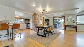 A spacious kitchen with a dining area, featuring a brick column, modern appliances, and a large window.