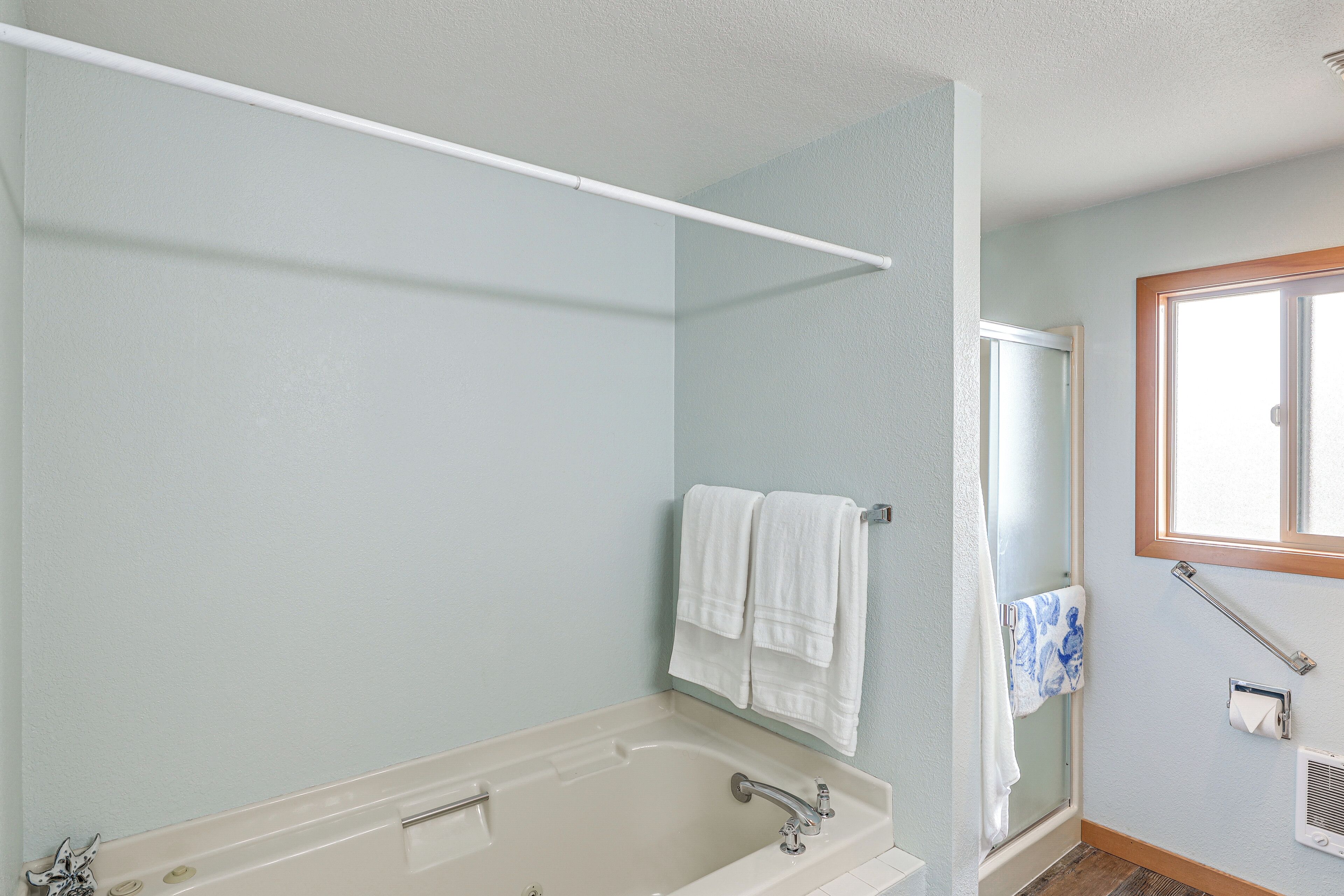 Un baño con bañera, ducha y ventana.