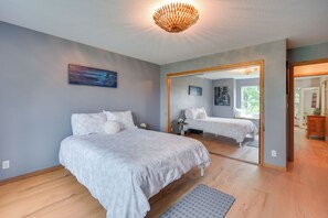 Une chambre à coucher avec un grand lit, un miroir et un luminaire fixé au plafond.