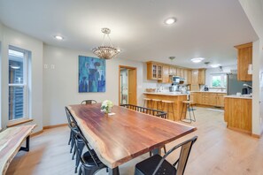 Une cuisine spacieuse avec des meubles en bois, une grande table à manger et un lustre.
