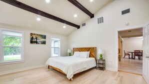 A bedroom with a wooden bed, a painting on the wall, and a view of the outdoors through a window. - Blue Ridge Retreat on 10-Acre Farm: Rural Reset! (Blue Ridge)