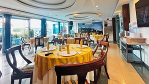 A restaurant with round tables, yellow tablecloths, and wooden chairs. - HOTEL LA CASCADA (Nueva Loja)