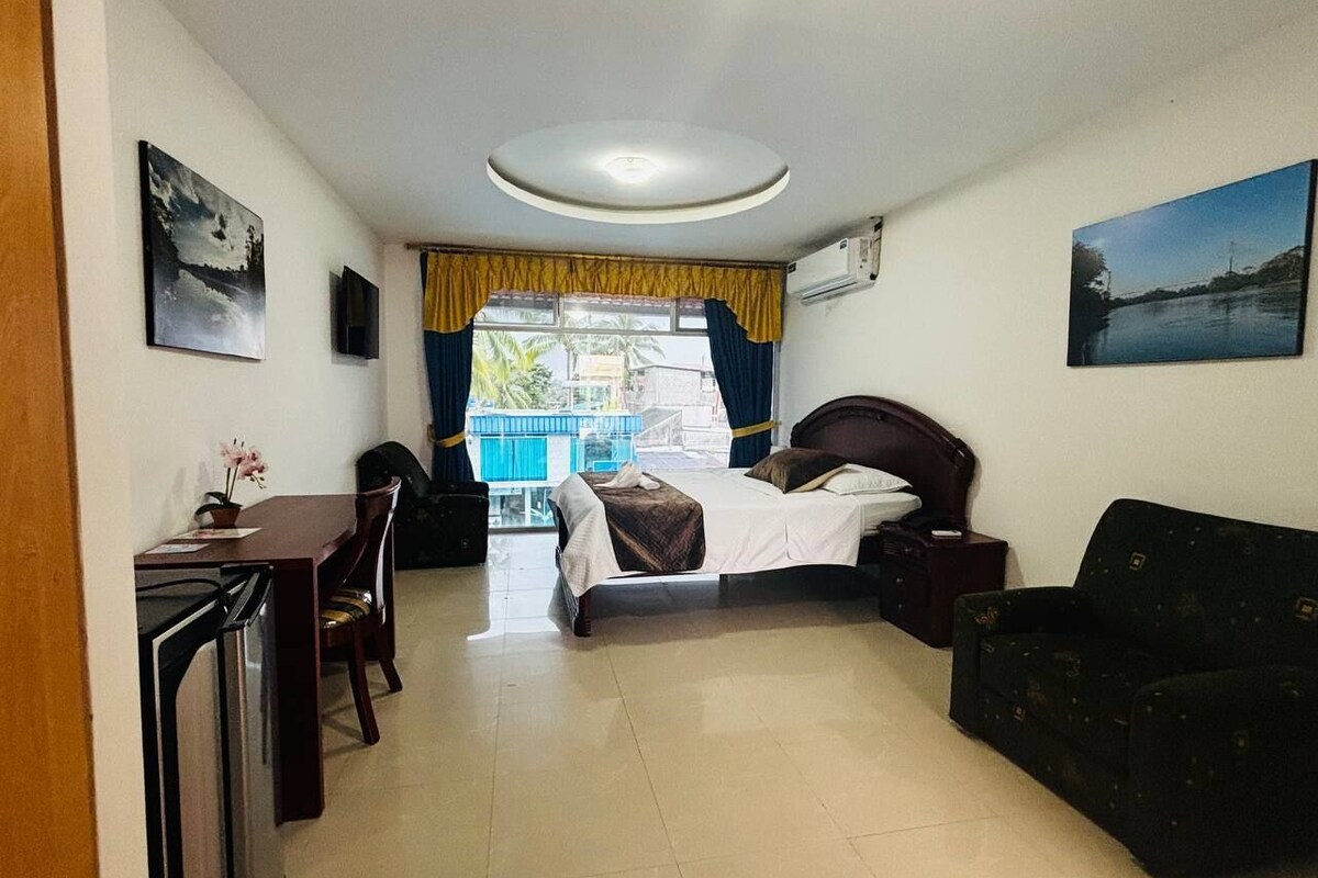 Camera d'albergo con un letto, una scrivania, una sedia, un divano e una finestra con tende.