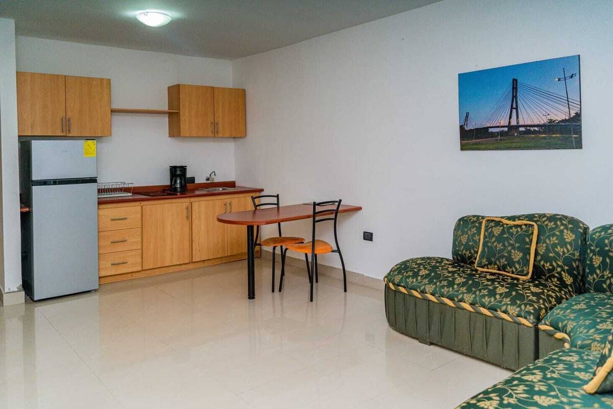 A compact living space with a kitchenette, a dining table, and a sofa.