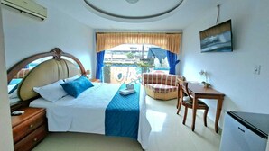 A bedroom with a bed, a desk, a chair, and a small table. - HOTEL LA CASCADA (Nueva Loja)