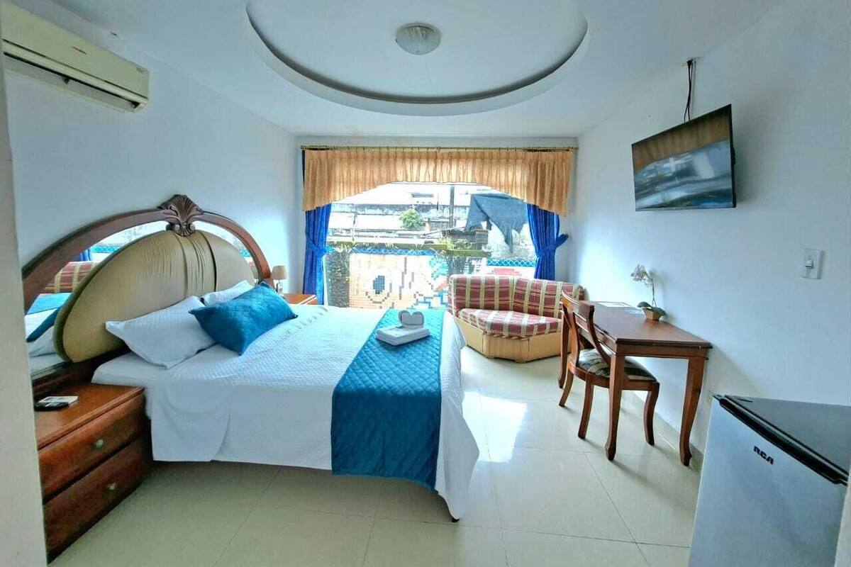 A bedroom with a bed, a desk, a chair, and a small table.