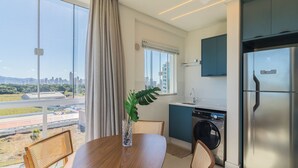 Eine moderne Küche mit Einbauwaschmaschine und Trockner, ein Essbereich mit Blick auf die Stadt und ein großes Fenster mit Vorhängen.