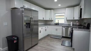 A modern kitchen with white cabinets, stainless steel appliances, and a granite countertop.
