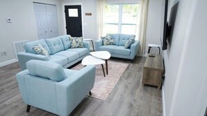 A living room with two light blue sofas, a white coffee table, and a wooden side table.