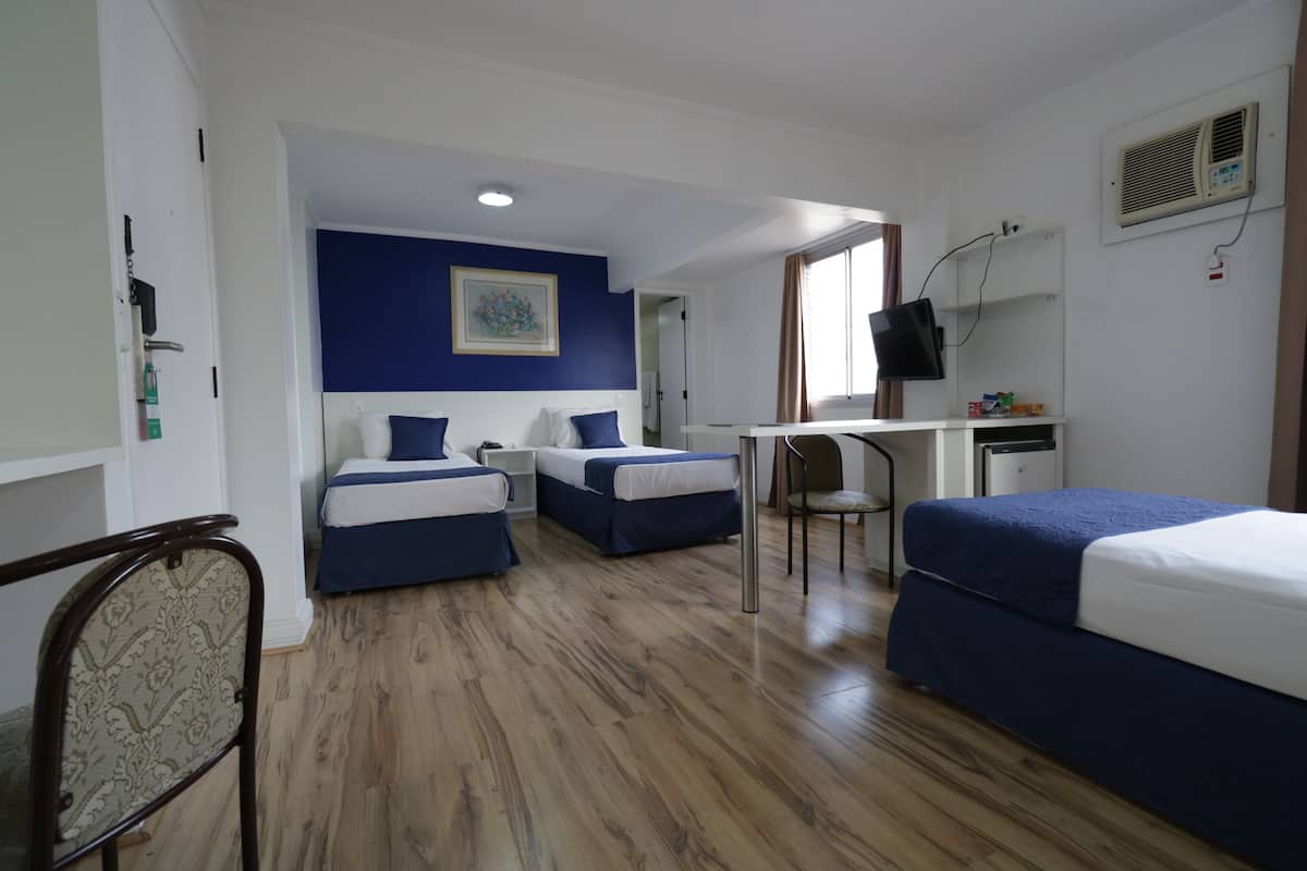 Une chambre d’hôtel avec deux lits, un bureau, une chaise et un téléviseur.