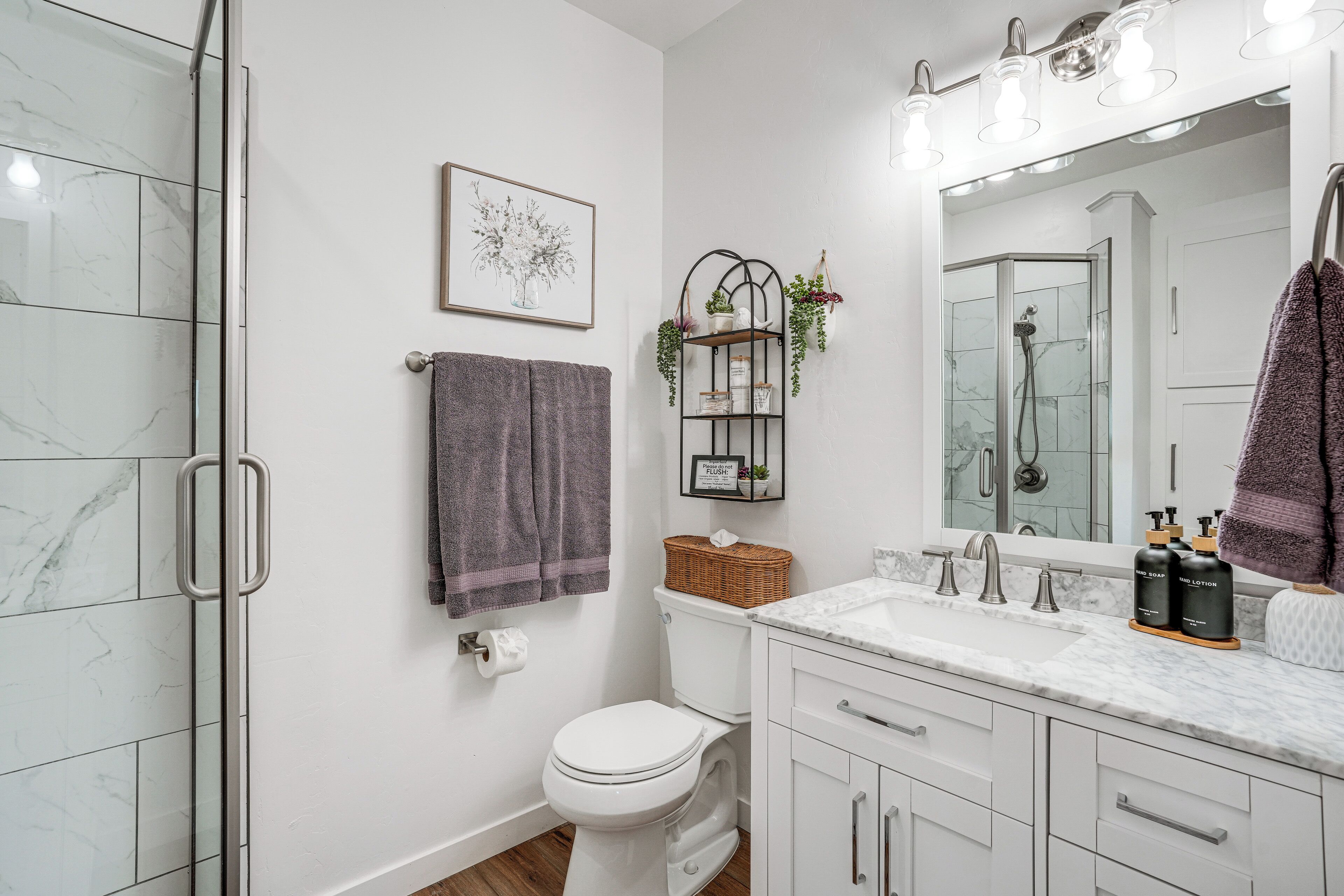Un baño moderno con cabina de ducha de vidrio, inodoro, tocador con espejo y barra para toallas.