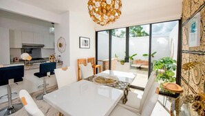 A modern kitchen with white cabinets, a stainless steel range hood, and a dining area with a white table and chairs. - Charming & Comfortable House, 15 min to Downtown (Playa del Carmen)