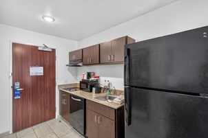 Uma cozinha compacta com geladeira, micro-ondas, cafeteira e pia.