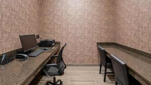 Un petit bureau fermé, comprenant deux bureaux : l’un est équipé d’un ordinateur et d’un clavier, l’autre d’une imprimante. Des chaises et un téléphone se trouvent sur les bureaux.