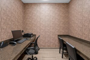 Un petit bureau fermé, comprenant deux bureaux : l’un est équipé d’un ordinateur et d’un clavier, l’autre d’une imprimante. Des chaises et un téléphone se trouvent sur les bureaux.