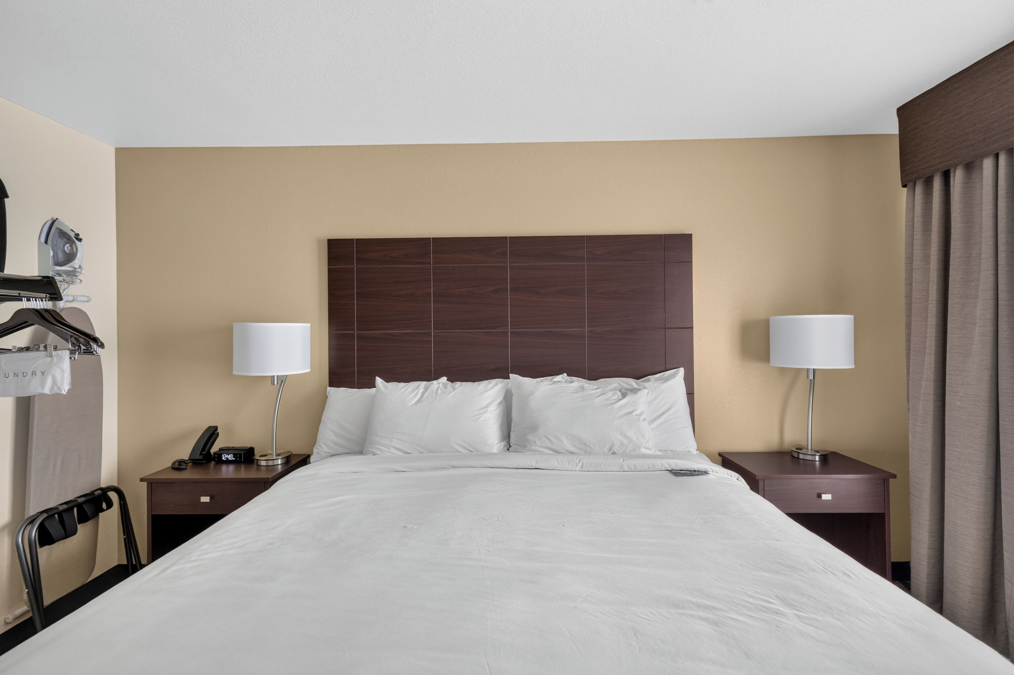 Habitación de hotel con una cama grande, dos mesitas de noche, un armario y una lámpara.