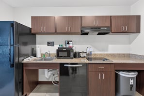 A modern kitchen with wooden cabinets, a stainless steel refrigerator, a microwave, and a dishwasher. - Cobblestone Hotel & Suites - Waukesha/West Milwaukee (Waukesha)