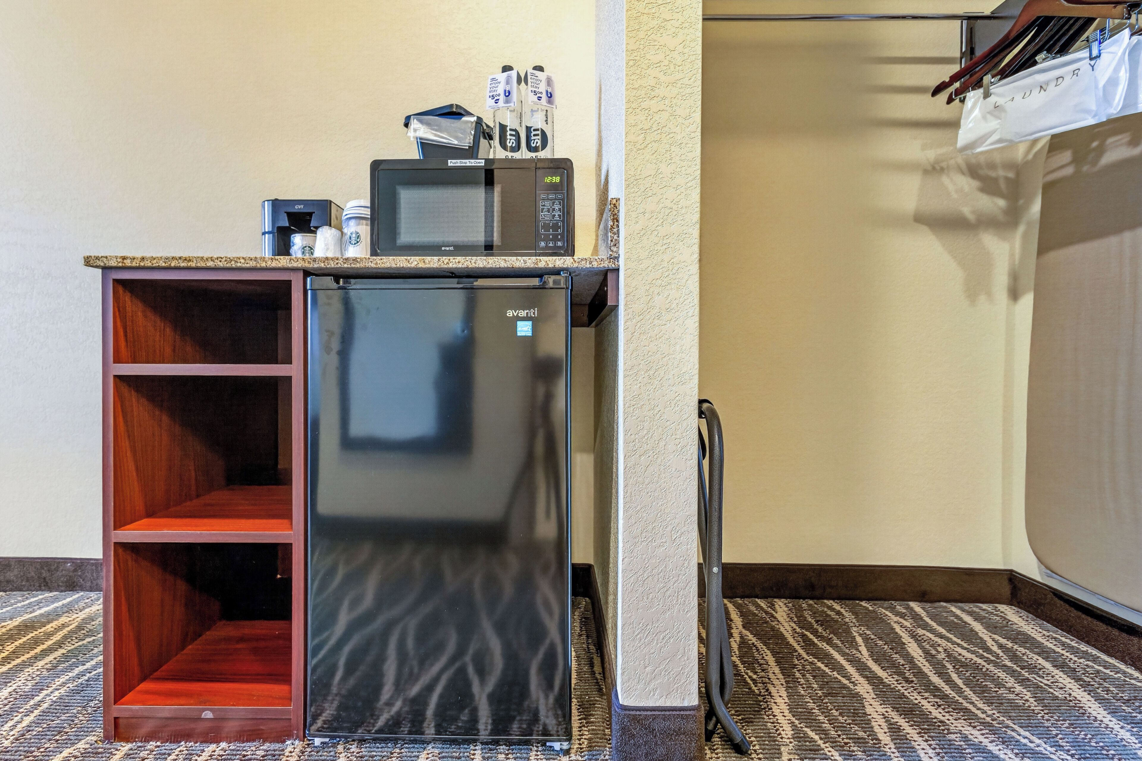 A compact kitchenette with a microwave, coffee maker, and storage for condiments.