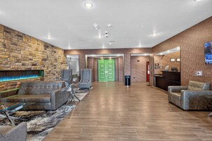 Un vestíbulo con pared de piedra, sofás de cuero, una puerta verde y una recepción.