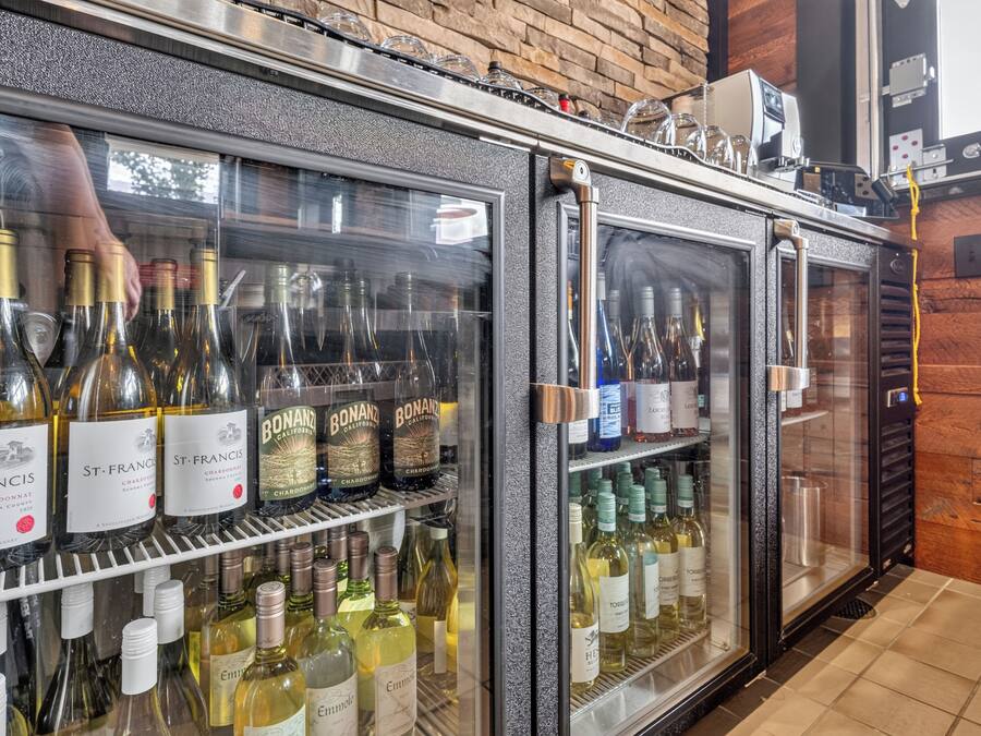 A bar area with a wine refrigerator stocked with various bottles.