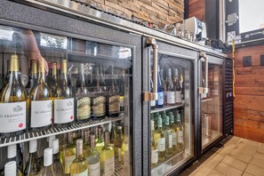 Una zona de bar con un refrigerador de vinos repleto de botellas variadas.