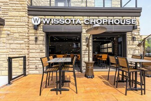 Un área de estar al aire libre con mesas y sillas frente a un edificio con la leyenda 'WISSOTA CHOPHOUSE'.