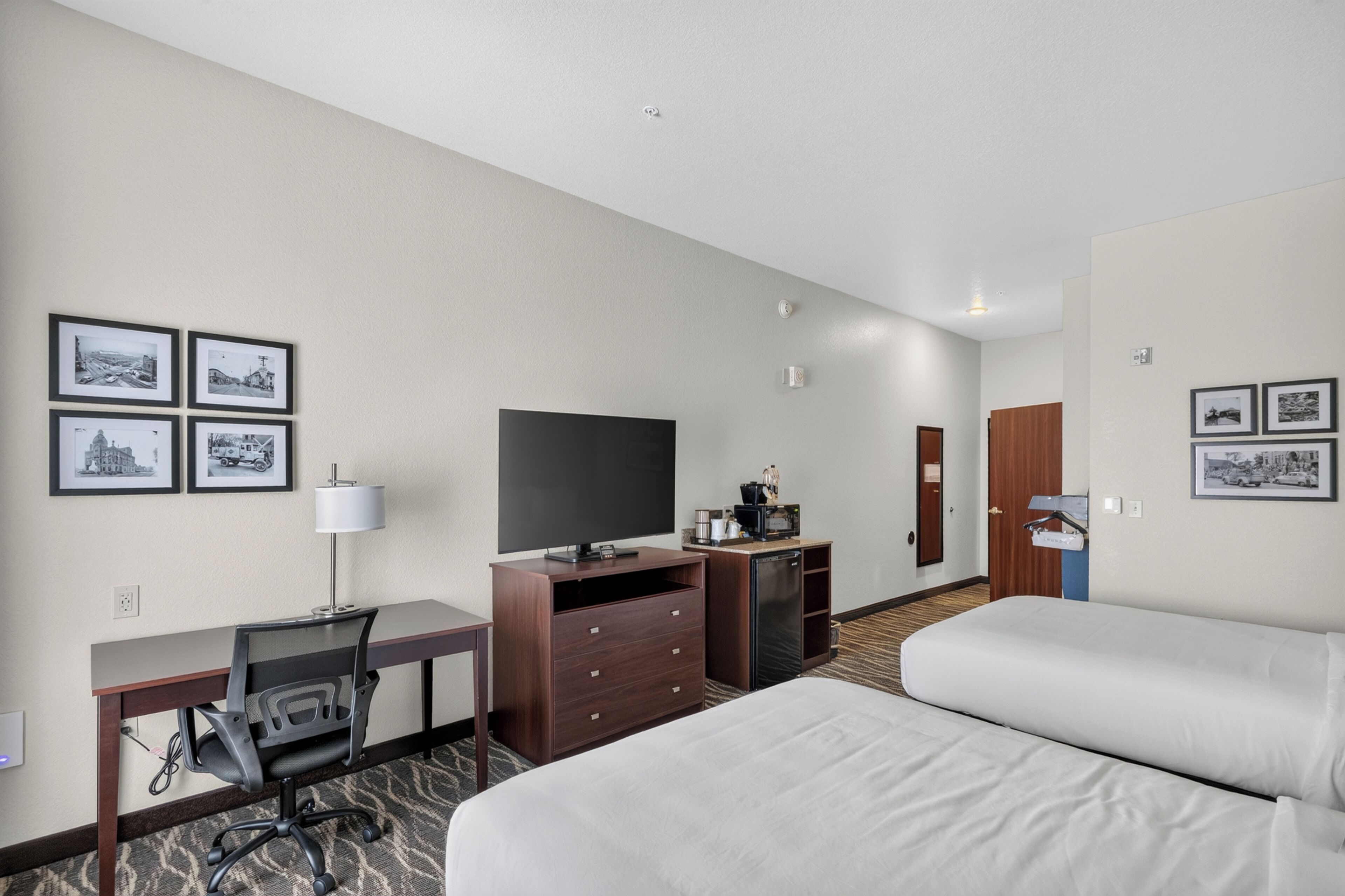 Une chambre d’hôtel équipée d’un lit, d’un bureau, d’une chaise, d’une télévision et d’une petite kitchenette.