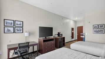 Une chambre d’hôtel équipée d’un lit, d’un bureau, d’une chaise, d’une télévision et d’une petite kitchenette.