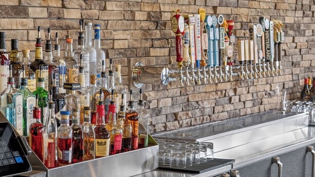 A bar area with a variety of liquor bottles and a tap system. - Cobblestone Hotel & Suites - Waukesha/West Milwaukee (Waukesha)