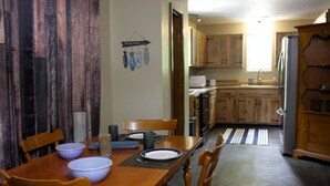 A dining area with a wooden table, chairs, and a kitchen in the background.