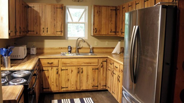 A kitchen with wooden cabinets, a stainless steel refrigerator, a stove, and a window.