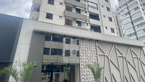 A high-rise building with multiple balconies and a modern entrance with glass doors.