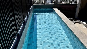 A swimming pool with a checkered tile pattern and a metal railing on one side.