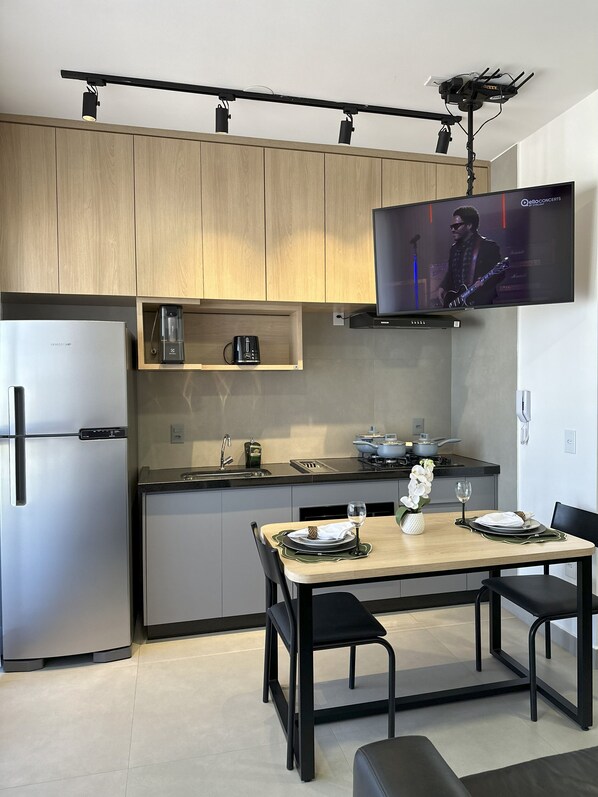 Una cocina moderna con un refrigerador empotrado, un microondas y un televisor de pantalla plana montado en la pared.