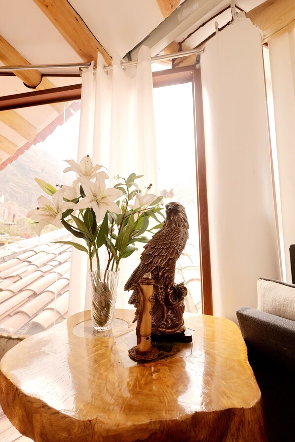 A wooden table with a vase of white flowers and a bird sculpture.