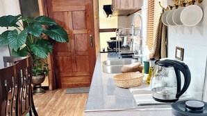 Una cocina compacta con puerta de madera, un lavamanos, una tetera y una licuadora en la encimera.